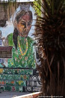Arte callejero de una mujer vestida de verde alrededor de la plaza de estudiantes de Camiri.