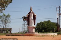 Tall statue of Christ the King at the end of a long road in Robore, a lookout tower is behind.