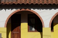Prdio com arcos de tijolo, telhado de telha, portas e janelas de madeira e pintado de amarelo em San Ignacio de Velasco.