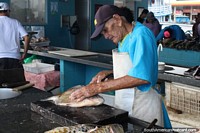 A man cuts and fillets a fish at the market in Santarem. Brazil, South America.