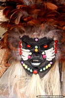 Uma máscara de madeira assombrosa com contas coloridas e penas da venda de uma loja de arte em Alter do Chao perto de Santarem. Brasil, América do Sul.