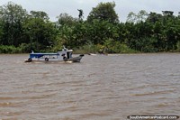 Um pequeno barco de passageiros e uma canoa de rio cruzam caminhos ao oeste de Belém. Brasil, América do Sul.