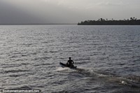 El chico en una canoa dirige hacia el atardecer en el día final en el viaje desde Belem a Macapá. Brasil, Sudamerica.