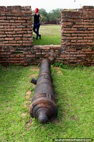 Un cañón apunta a una chica con el pelo teñido de rojo en el Macapá fortaleza. Brasil, Sudamerica.