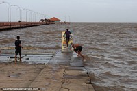 Boy rides a bike on a ramp into the Amazon River in Macapa.