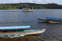 Passenger boats cross paths on the Oyapock River in Oiapoque, the border of Brazil and French Guiana. Brazil, South America.