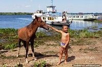 Boy and his horse, passenger boats in the river in Neopolis. Brazil, South America.