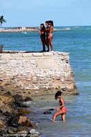 Women enjoying the sun and sea around the rocks at Pajucara Beach in Maceio.