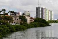 As margens do rio verde e os prédios que se misturam à paisagem do Recife. Brasil, América do Sul.