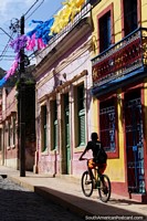 Man rides a bike up the old streets of Olinda, iron balcony and cobblestone street. Brazil, South America.