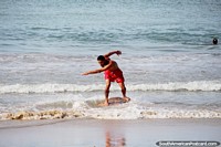 Versão maior do O homem patina ao longo da água em uma tábua de madeira em Praia de Golfinho, Pipa.
