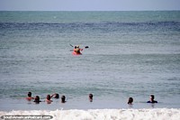 Versão maior do Pessoas em um caiaque que espera por delfins para emergir na praia em Pipa.