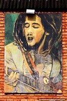 Bob Marley singing and playing guitar, a worn mural in Pipa. Brazil, South America.