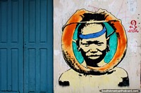 Larger version of Indigenous man surrounded by orange tusks, street art in Rio Branco.