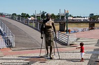 Child interacts with bronze figure of a woman in front of the bridge over the Acre River in Rio Branco. Brazil, South America.