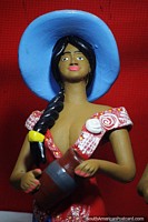 Una mujer con un gran sombrero azul sostiene una urna, una variedad de figuras en venta en Porto Velho. Brasil, Sudamerica.