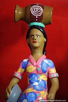 La mujer con un vestido floral rosado y azul tiene una urna en la cabeza, cerámica en Porto Velho. Brasil, Sudamerica.