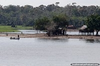 Larger version of The journey on the Amazon River continues, stilt houses and people in a small boat.