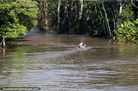 Riverboat speeds away into the dense jungle river system. Brazil, South America.