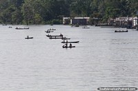 Children of an indigenous village paddle canoes out to the passenger ferry in the Amazon.