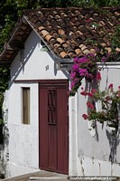 Telhado vermelho e flores, uma fachada de casa branca em Carolina.