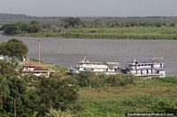 Small ferry boats docked in Corumba, the Paraguay River and distant green wilderness of the Pantanal. Brazil, South America.