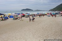 Larger version of Santinho Beach with rocky surrounding cliffs and surfing in Florianopolis.