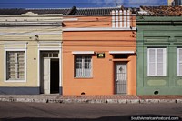 Orange, cream and green colored houses on a street in Pelotas.