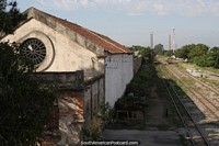 Train tracks in Pelotas, a round window and distant brick smoke tower.