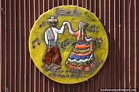 Gaucho couple in traditional dress dance to music, ceramic art in Alegrete.
