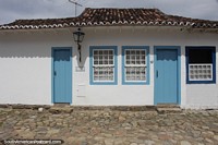Colonial house with wooden doors and tiled roof on a cobblestone street in Paraty.