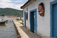 Arts market on the seafront in Paraty with masks decorating the building.