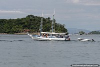 Embarcao de mdio porte com passageiros navega pela baa de Paraty.