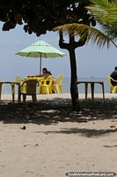 Enjoy a table at the beach under an umbrella in Mambucaba.