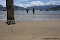 Antiguos pilones del muelle en la arena y el agua en la playa de Saco en Mangaratiba.