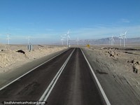Um campo de moinhos de vento que geram poder de Calama junto do caminho. Chile, América do Sul.