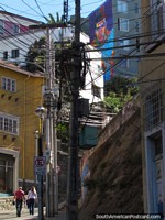 People walk up the step hill to see the mural and neighborhood at the top in Valparaiso.
