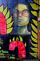 Una persona indígena Mapuche con pintura facial roja, arte callejero en Valdivia. Chile, Sudamerica.