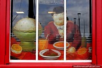 Homem a uma mesa de jantar, pinturas nas janelas do Tablon do Ancla Restaurante em Porto Montt. Chile, América do Sul.
