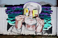 Versión más grande de Arte callejero en Osorno, el hombre tiene 2 cartas frente a sus ojos.