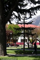 Larger version of The beautiful Plaza de Armas in Coyhaique with trees and lawns, snow-capped mountains in the distance.
