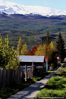 Suburban street with many colorful trees and snowy mountains behind in Cochrane. Chile, South America.