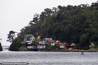 Wooden houses, some on stilts on the waters edge at Puerto Gala. Chile, South America.