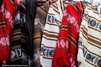 Red, brown and white ponchos with traditional designs, made in Castro. Chile, South America.