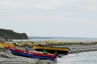 Um par de barcos põe-se em uma praia cheia de pedras na costa ao leste de Porvenir. Chile, América do Sul.