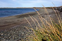 Long stony beach curves around the bay of Bahia Azul in the Tierra del Fuego.