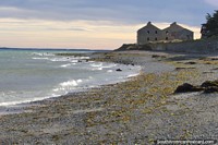 San Gregorio, uma praia cheia de pedras e litoral 90 minutos de Punta Arenas, edifïcios não usados distantes. Chile, América do Sul.
