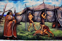 Indigenous people building a tent in the wilderness, mural by Eladio Godoy Vera in Puerto Natales. Chile, South America.