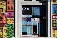 Girl and cat look out from a window, a painting on a window in Valparaiso.