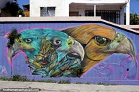 Eagles, green and orange, a face emerges, street art on a purple wall in Valparaiso. Chile, South America.
